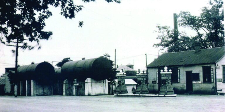 1931 : photo dla station Reighard montrant des pompes en brique, une aire de service non couverte et des réservoirs hors sol (© Facebook)