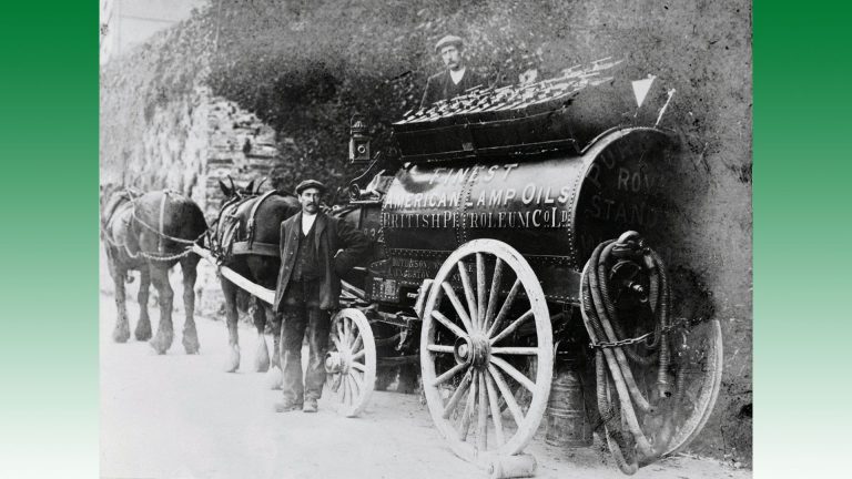 Les chauffeurs-livreurs sont à côté de leur véhicule. Les wagons-citernes tirés par des chevaux, utilisés pour la distribution de produits pétroliers, ont remplacé les charrettes chargées de tonneaux des années 1880