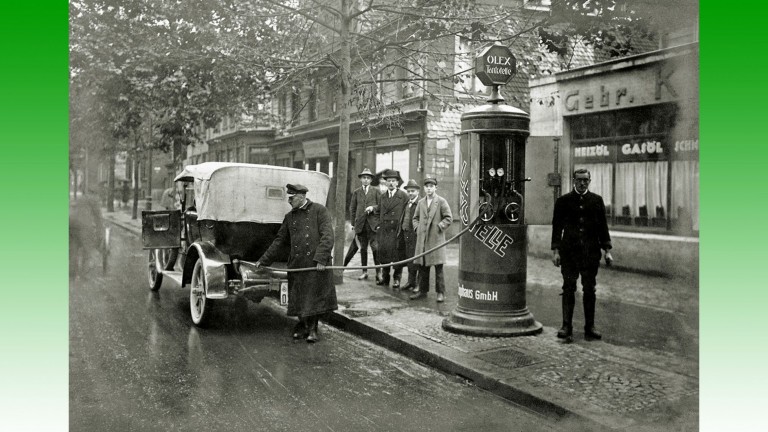 Un préposé au ravitaillement d'une automobile dans une petite station-service Olex en bordure de route en Allemagne au cours des années 1920