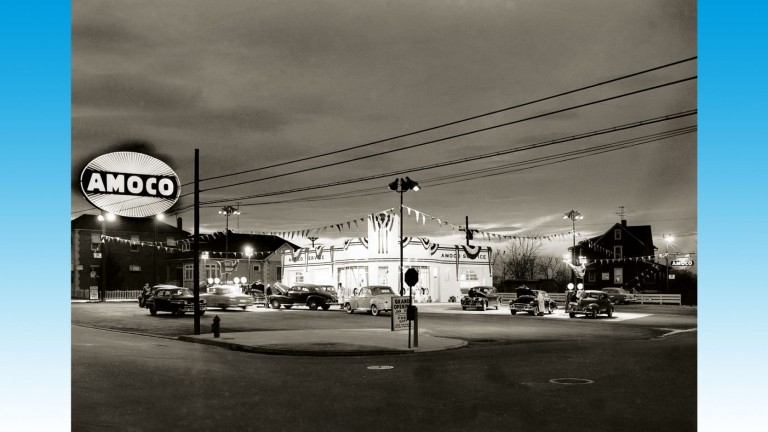 L'ouverture d'une nouvelle station-service Amoco près de Baltimore, aux États-Unis, en 1953. Des banderoles bordent le parking, juste devant le magasin éclairé
