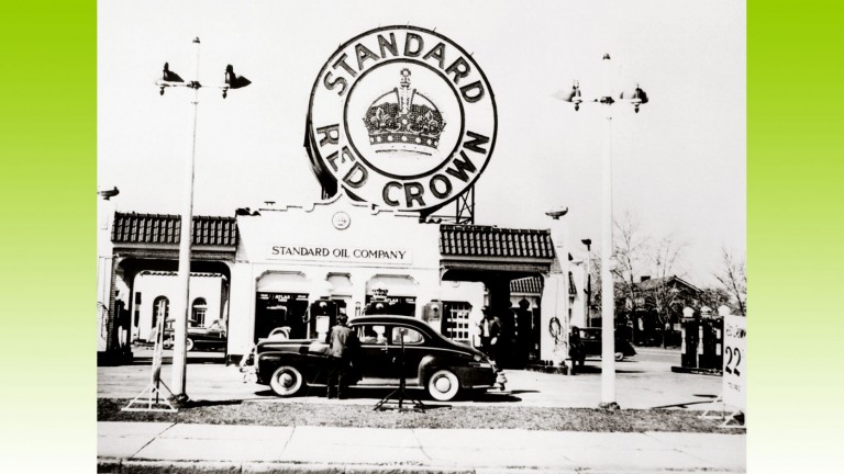 Une des premières stations-service de la Standard Oil Company. Un énorme panneau, situé sur le toit de la station-service, annonce l'essence standard Red Crown