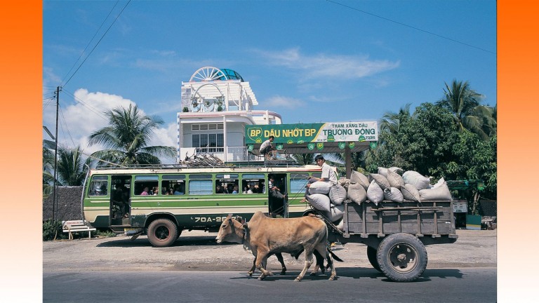 Ravitaillement dans une station-service BP à Truong Dong, dans la région du delta du Mékong au Vietnam, 1994. Des buffles d'eau tirent une charrette d'agriculteur au premier plan
